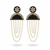 Pair of earrings with black floral tops and gold chains on a white background